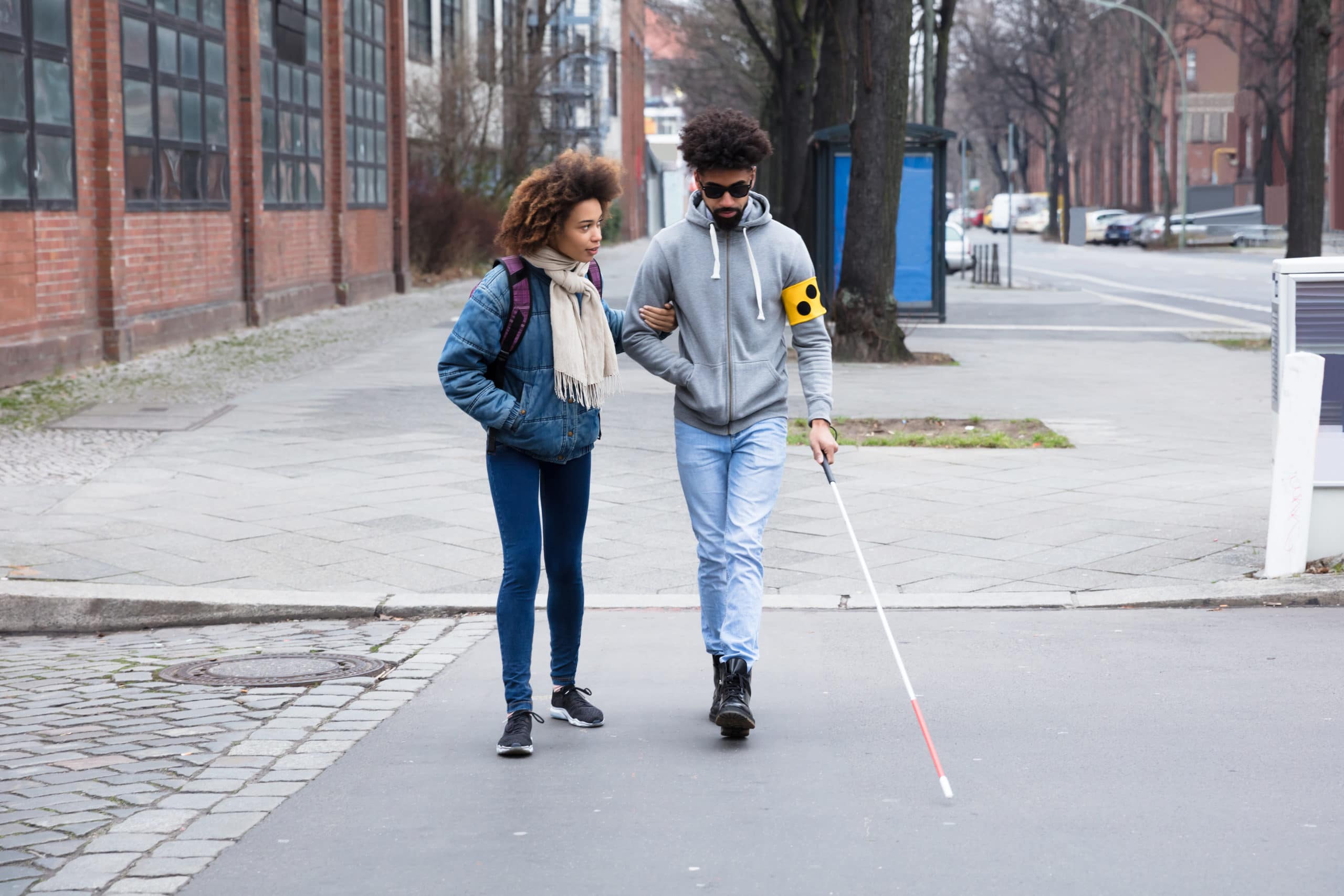 2 women walking, one os walking with a white cane
