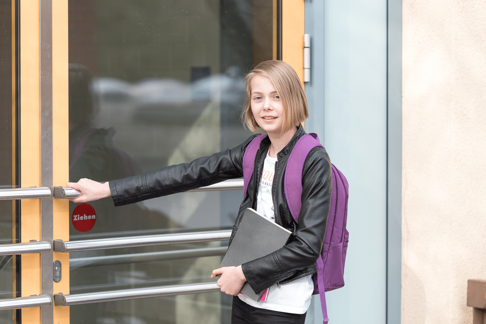 Young student with backpack entering building