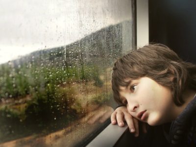 Young boy looking out a rainy window