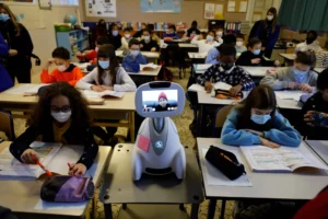 Students in class with a robot on a desk projecting a kid's face