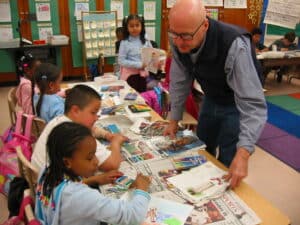 Teacher standing over two students at a desk
