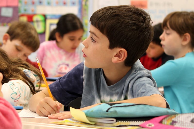 Young student writing with a pencil at desk