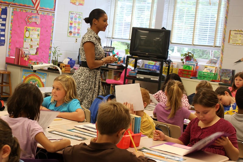 Teacher walking through classroom where young students are working