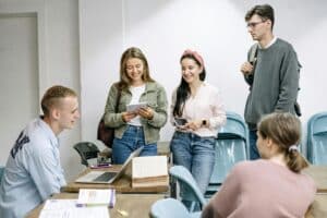 Five adults standing around a table chatting. 