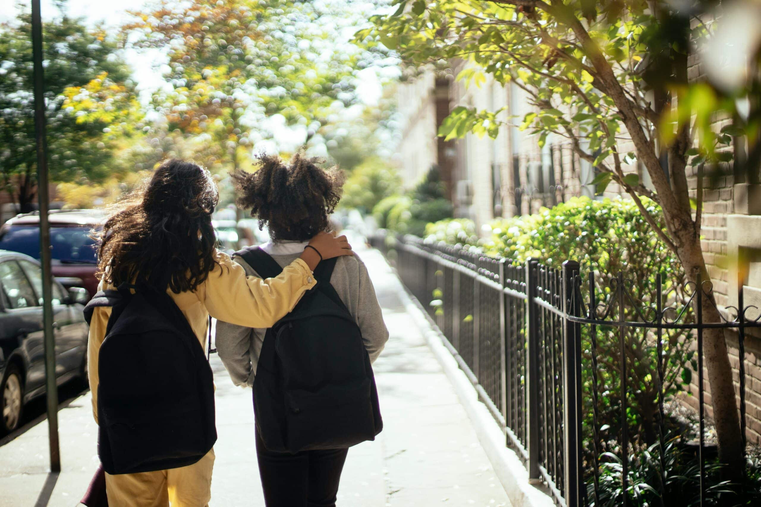 Two kids walking together, arm in arm, on the sidewalk