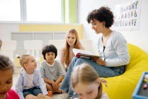 Adult reading a book to three young students