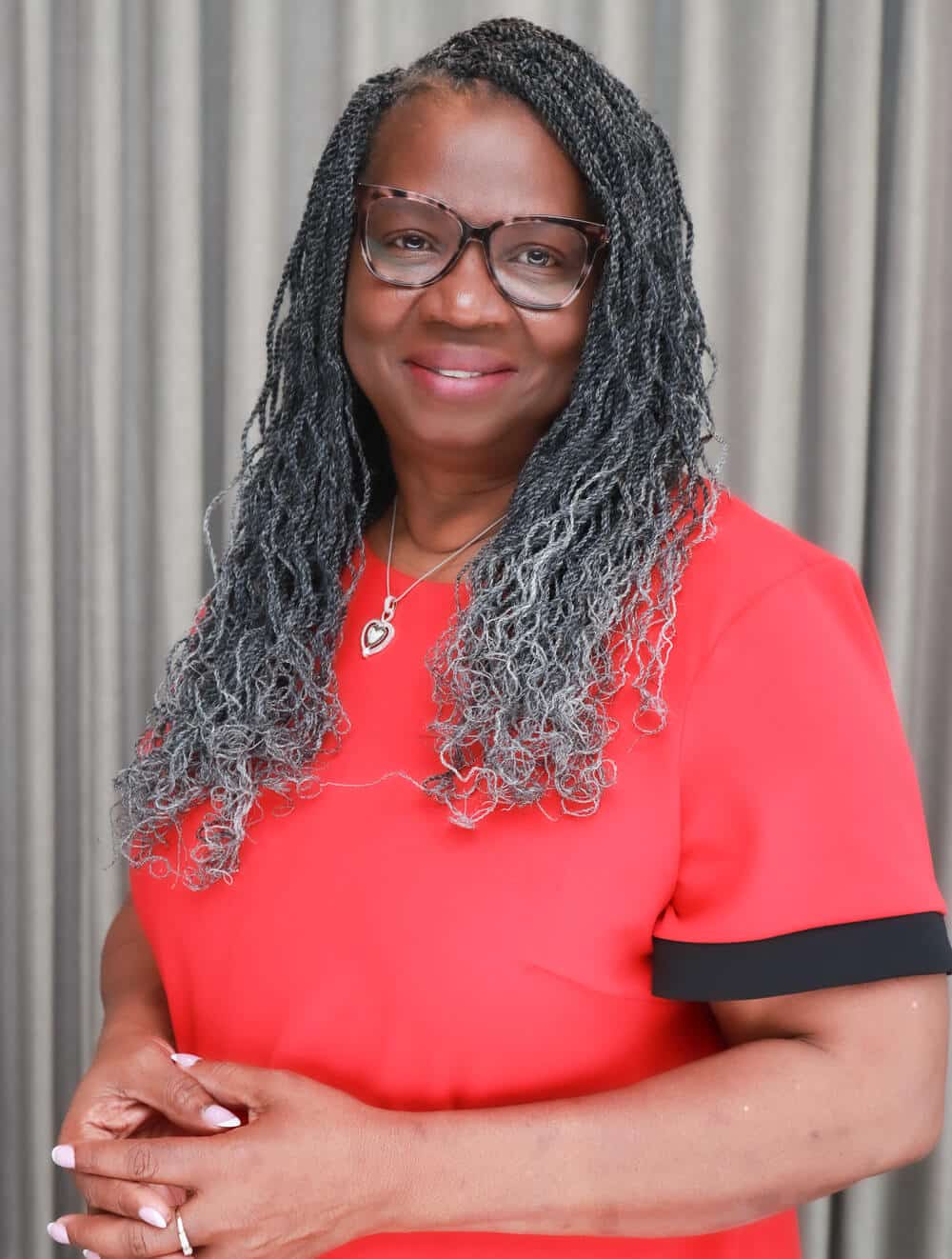 A woman wearing glasses and a red shirt smiles at the camera.